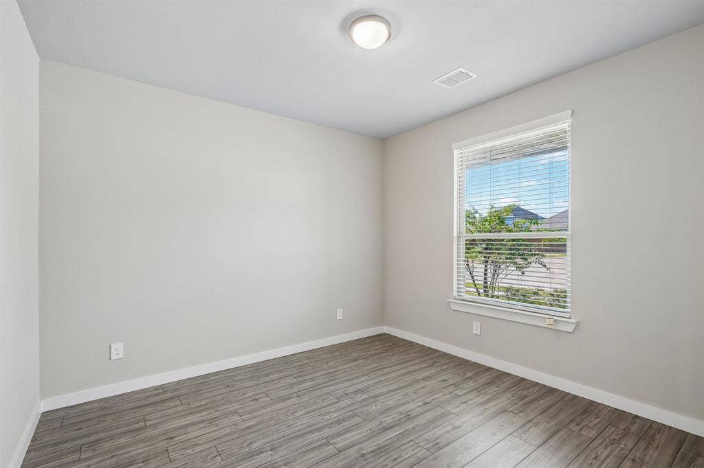 135 Lost Maples Way, Waxahachie, TX 75165 Neutral interior featuring wood-finish flooring, light-toned walls, and a single-pane window with adjustable horizontal blinds