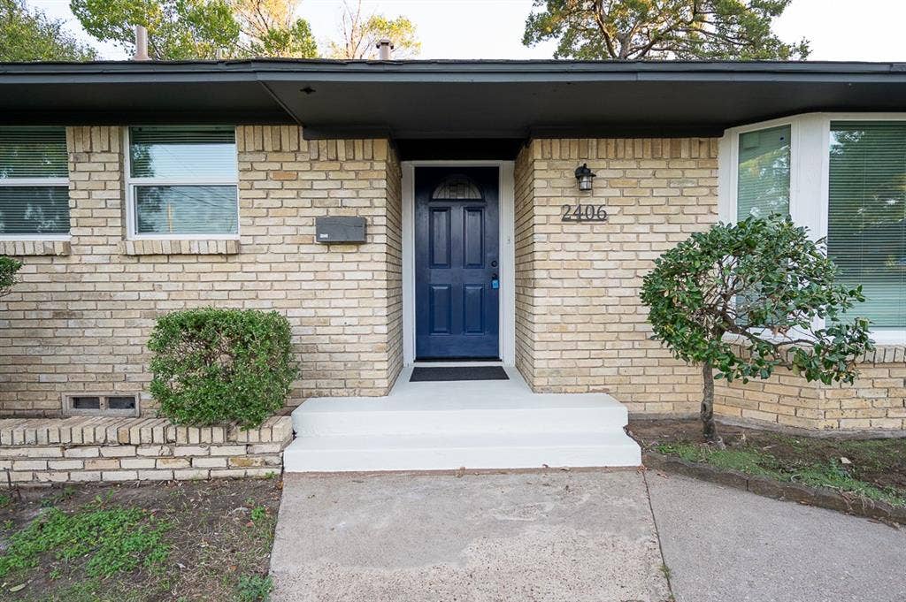 2406 Cliff Teen Court, Dallas, TX 75233 Exterior facade featuring light-toned brick masonry, a blue-painted front door with arched glass detail, and a bay window