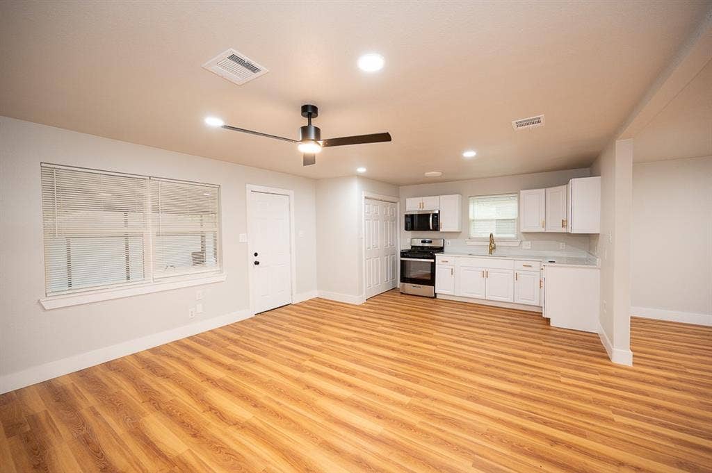 2406 Cliff Teen Court, Dallas, TX 75233 Open-concept interior featuring wood-finish flooring, white shaker cabinetry, stainless steel appliances, recessed lighting, and a modern ceiling fan