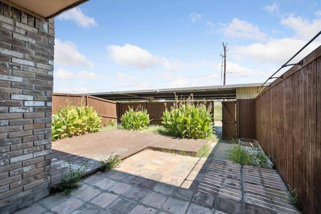 513 Towne House Lane, Richardson, TX 75081 Outdoor area featuring a wood deck, stone-paver patio, brick exterior wall, and wood privacy fencing