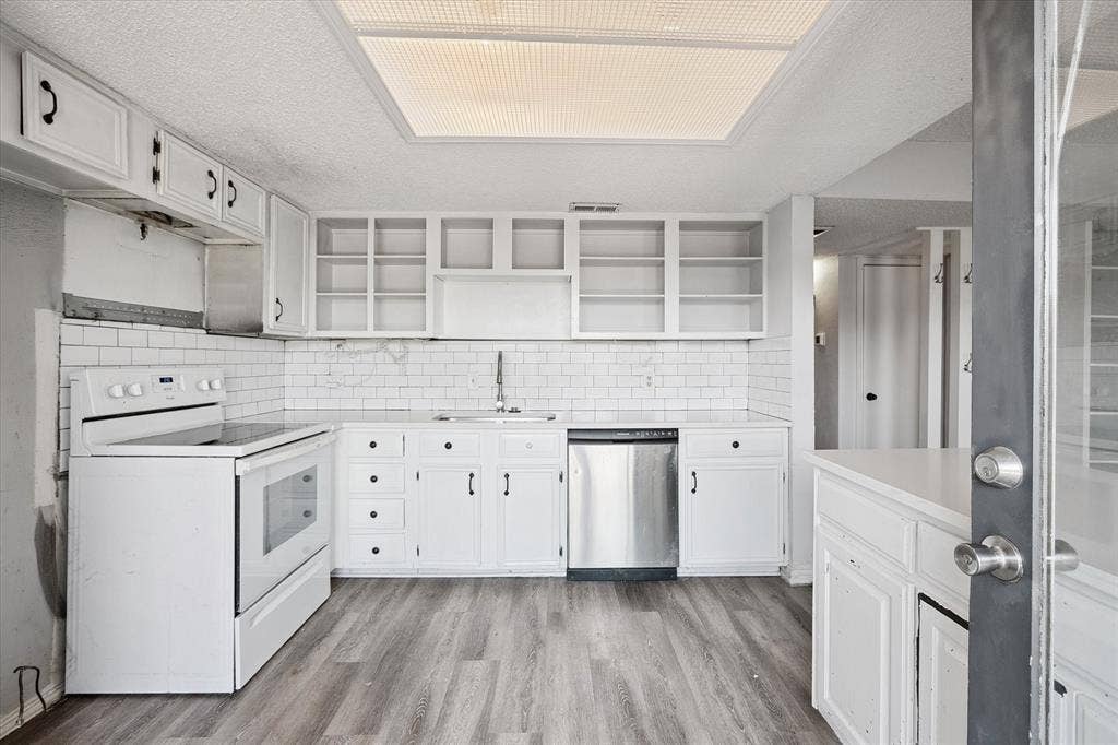 513 Towne House Lane, Richardson, TX 75081 Kitchen featuring white shaker-style cabinetry, open shelving, white subway tile backsplash, stainless steel dishwasher, and wood-finish flooring