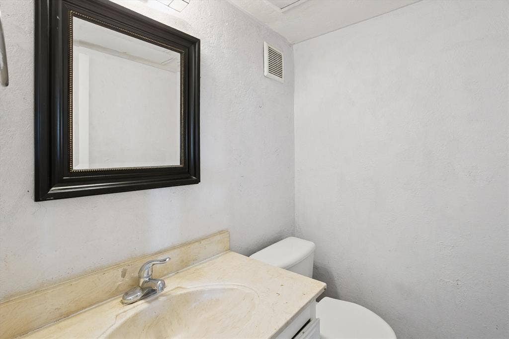 513 Towne House Lane, Richardson, TX 75081 Wall-mounted mirror with a black frame, vanity cabinet with an integrated sink, and polished metal faucet