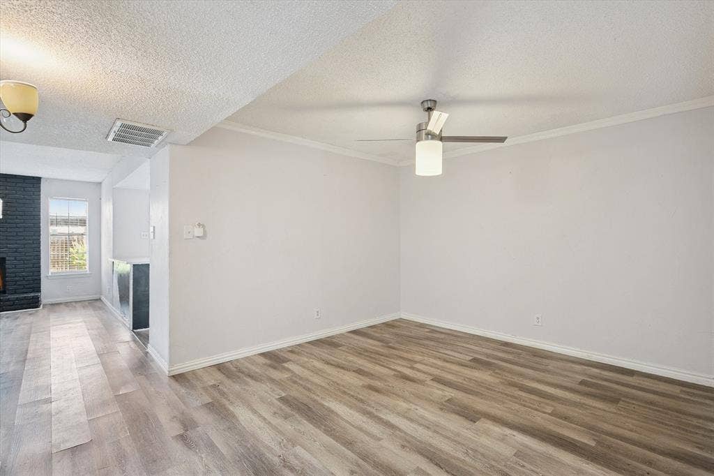 513 Towne House Lane, Richardson, TX 75081 Interior space featuring wood-finish flooring, a ceiling fan with integrated lighting, textured ceiling, and a painted brick fireplace surround