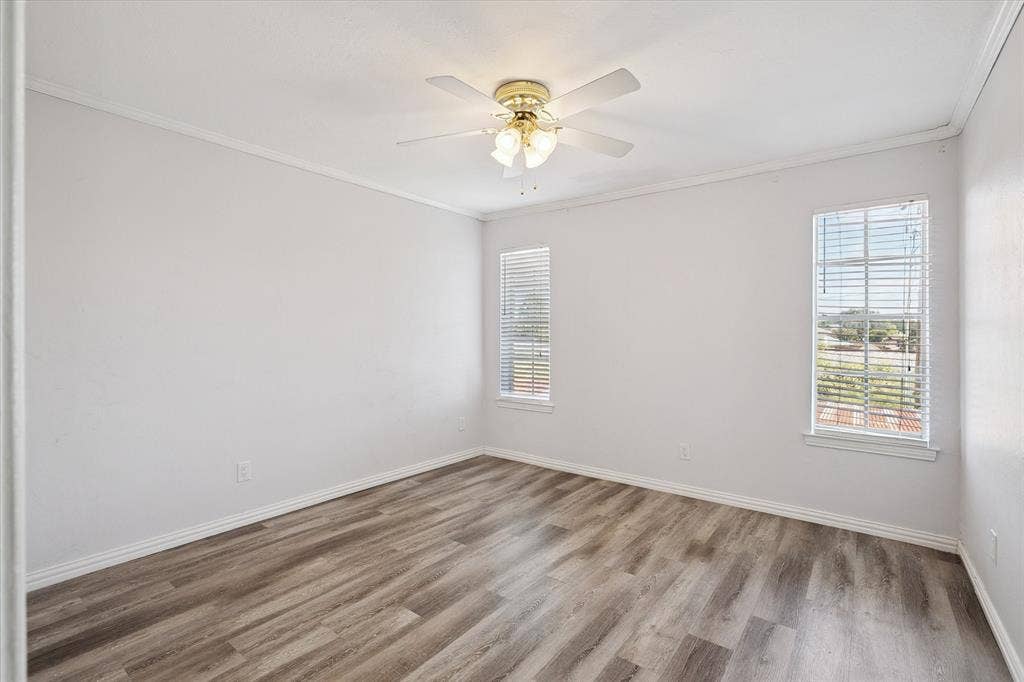 513 Towne House Lane, Richardson, TX 75081 Room with wood-finish flooring, neutral wall paint, dual windows with installed blinds, and a multi-blade ceiling fan with integrated light fixture