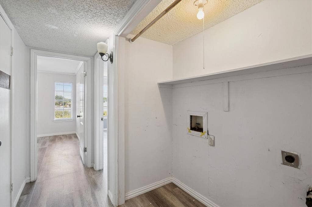 513 Towne House Lane, Richardson, TX 75081 Laundry area featuring wood-finish flooring, a built-in shelving unit, and a metal clothing rod