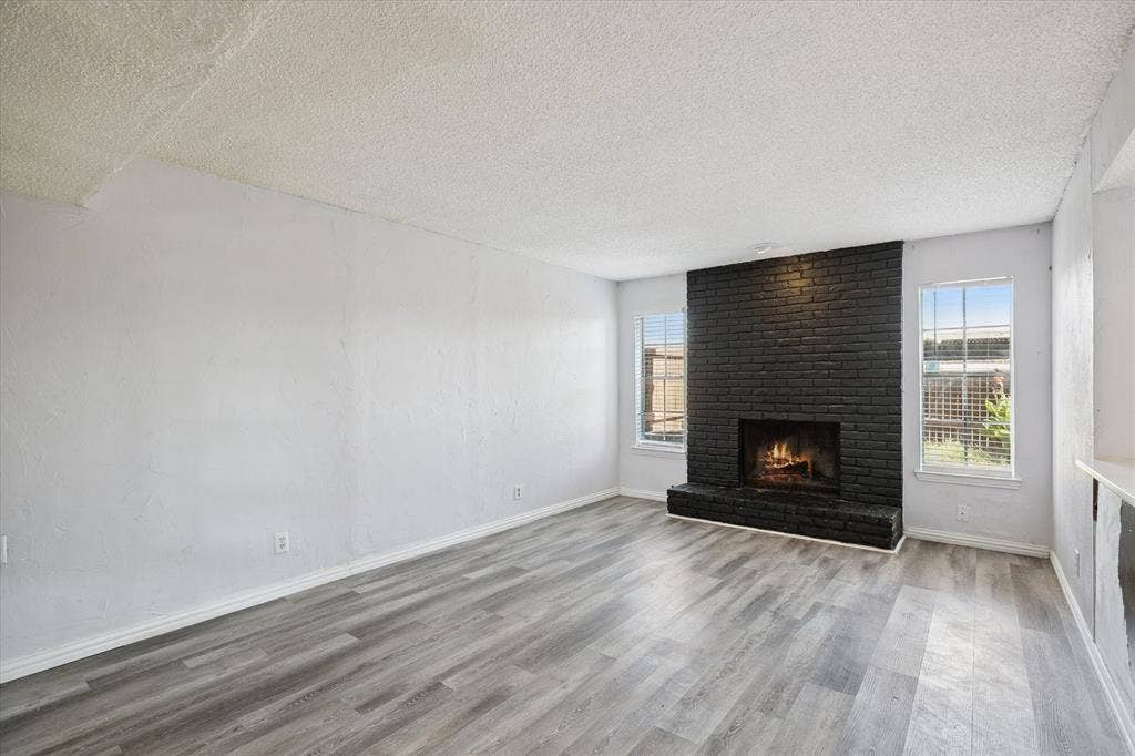 513 Towne House Lane, Richardson, TX 75081 Living area featuring wood-finish flooring and a floor-to-ceiling painted brick fireplace with a raised masonry hearth