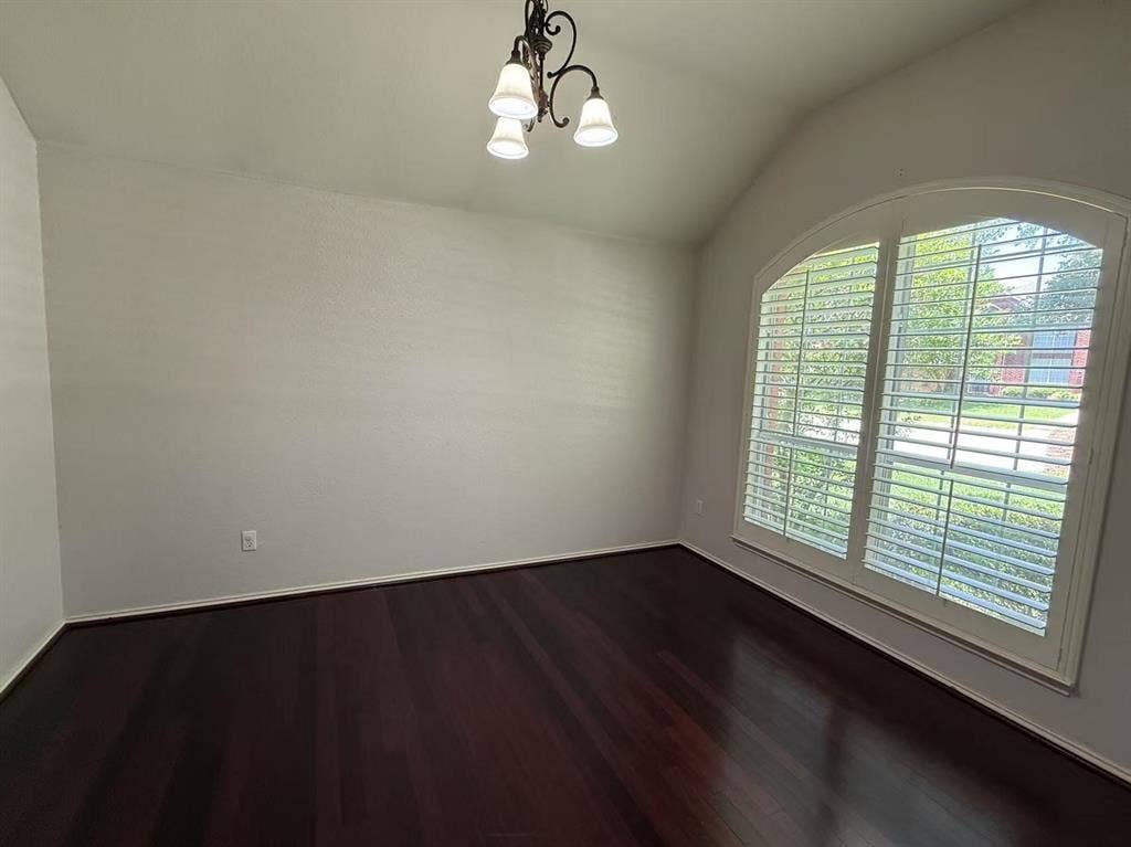 1307 Capstan Drive, Allen, TX 75013 Room featuring vaulted ceilings, wood-finish flooring, an arched window with plantation shutters, and a three-light chandelier