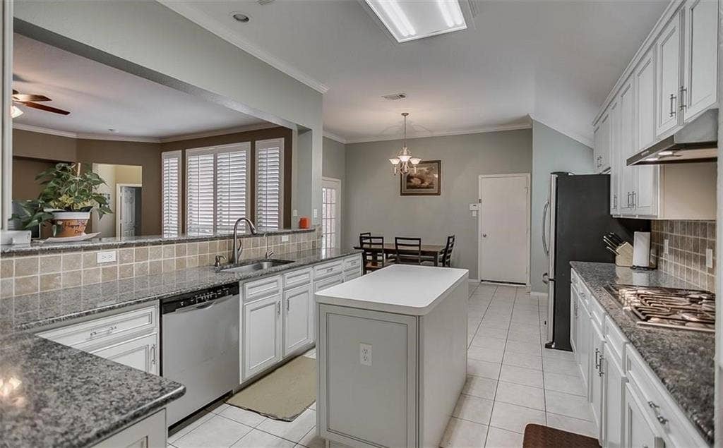 1307 Capstan Drive, Allen, TX 75013 Kitchen featuring white cabinetry, stone countertops, a center island with a solid surface top, tiled backsplash, and recessed ceiling lighting