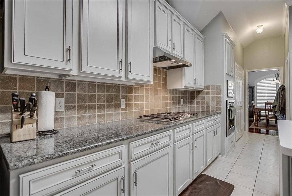 1307 Capstan Drive, Allen, TX 75013 Kitchen featuring crisp white shaker-style cabinetry, polished stone countertops, a neutral tiled backsplash, a built-in stainless steel gas cooktop, and a recessed wall oven