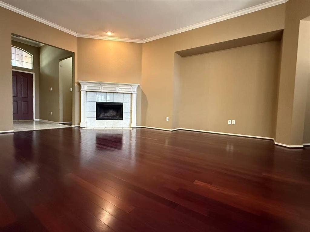 1307 Capstan Drive, Allen, TX 75013 Living area featuring wood-finish flooring, a corner fireplace with a decorative mantel, crown molding, and a recessed wall niche