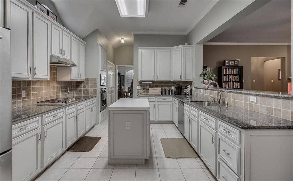 1307 Capstan Drive, Allen, TX 75013 Kitchen featuring white cabinetry, stone-surface countertops, central island, tiled backsplash, and stainless steel appliances