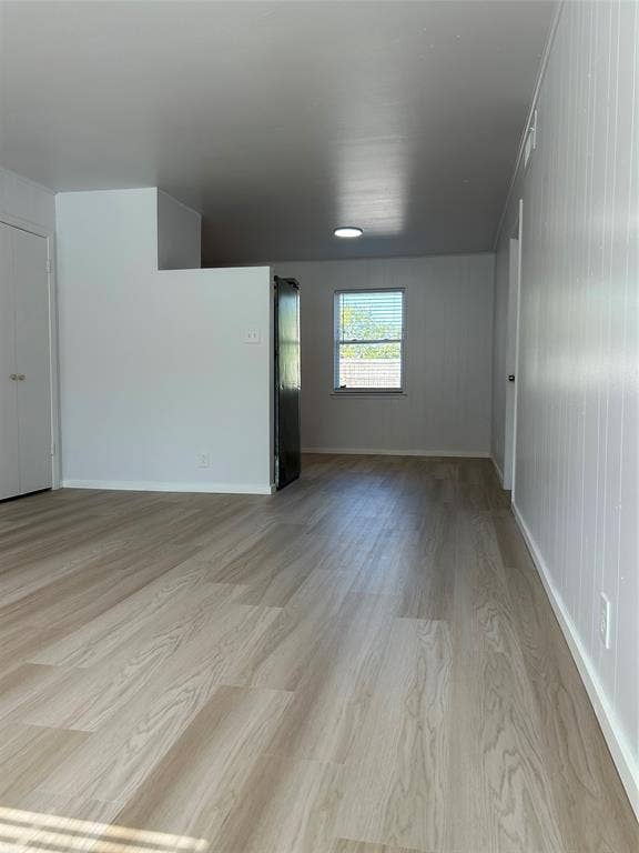 Neutral interior featuring light-tone wood-finish flooring, crisp white walls, and a recessed ceiling light fixture
