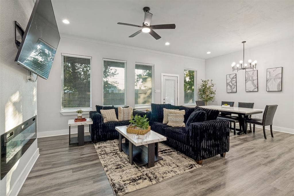 7909 Ivory Lane, Dallas, TX 75216 Open concept area featuring wood-finish flooring, recessed lighting, a modern wall-mounted electric fireplace, a multi-blade ceiling fan, and a multi-arm chandelier