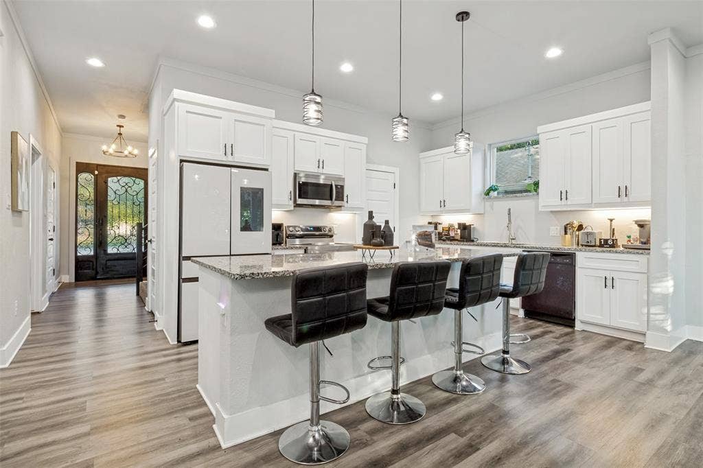7909 Ivory Lane, Dallas, TX 75216 Kitchen featuring white cabinetry, stone countertops, an expansive center island, recessed lighting, and wood-finish flooring