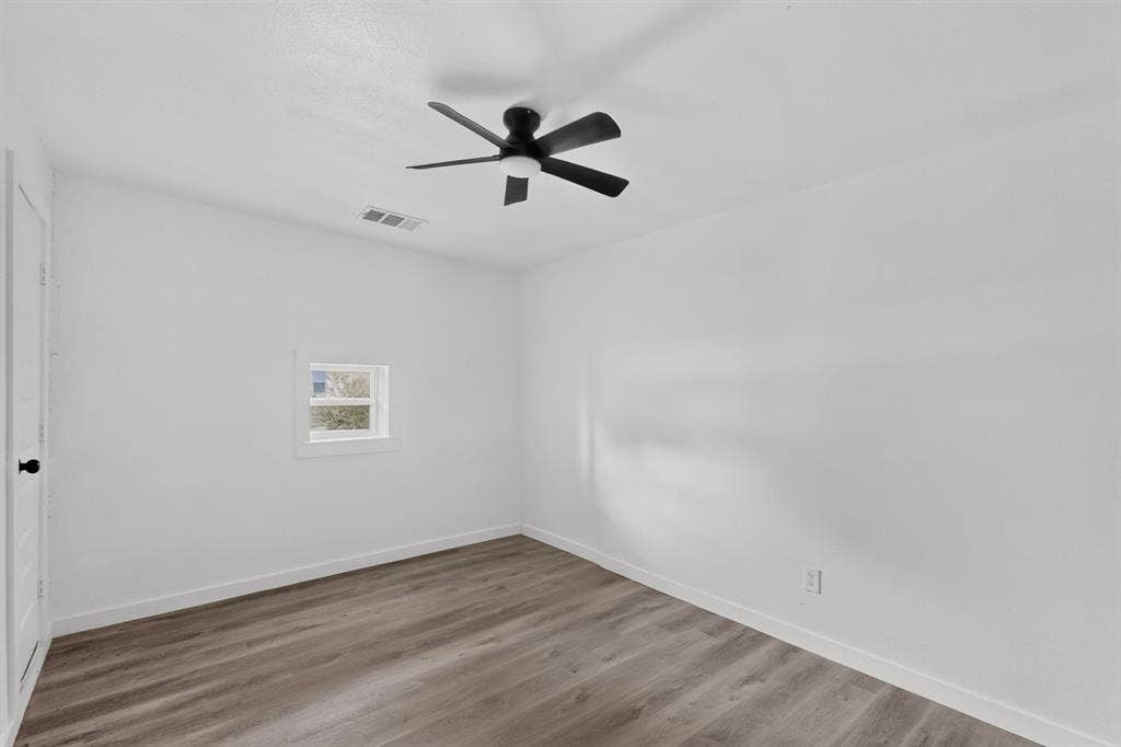 1831 Highland Street, Mesquite, TX 75149 Interior space featuring wood-finish flooring, white walls, a multi-blade ceiling fan with integrated lighting, and a window with white trim