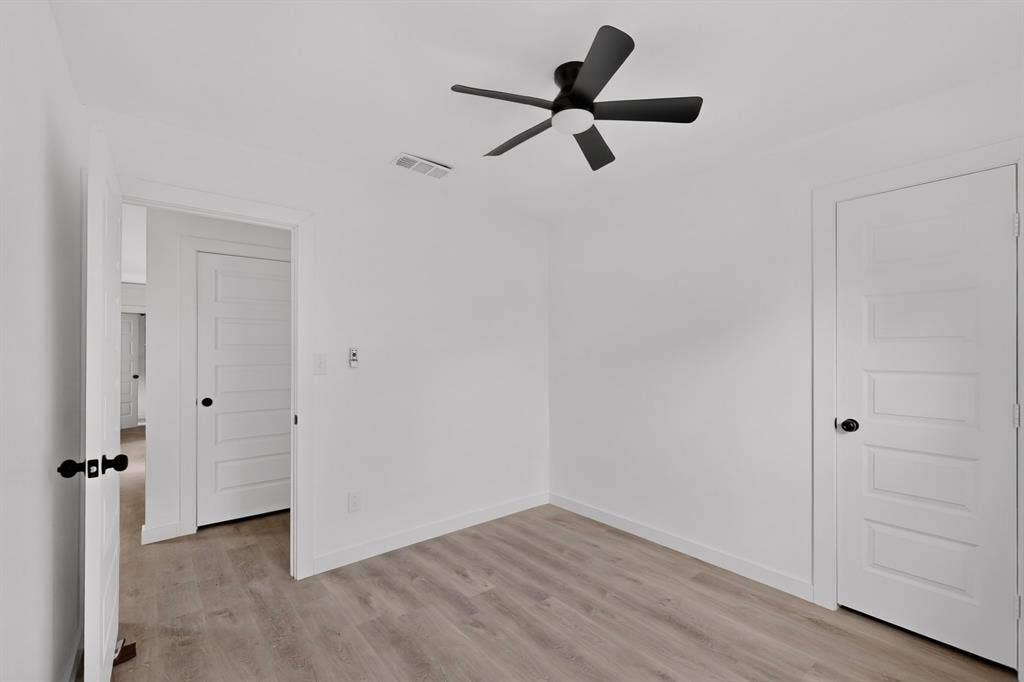 1831 Highland Street, Mesquite, TX 75149 Interior space featuring wood-finish flooring, five-panel shaker-style doors with matte black hardware, and a modern matte black ceiling fan with an integrated light fixture