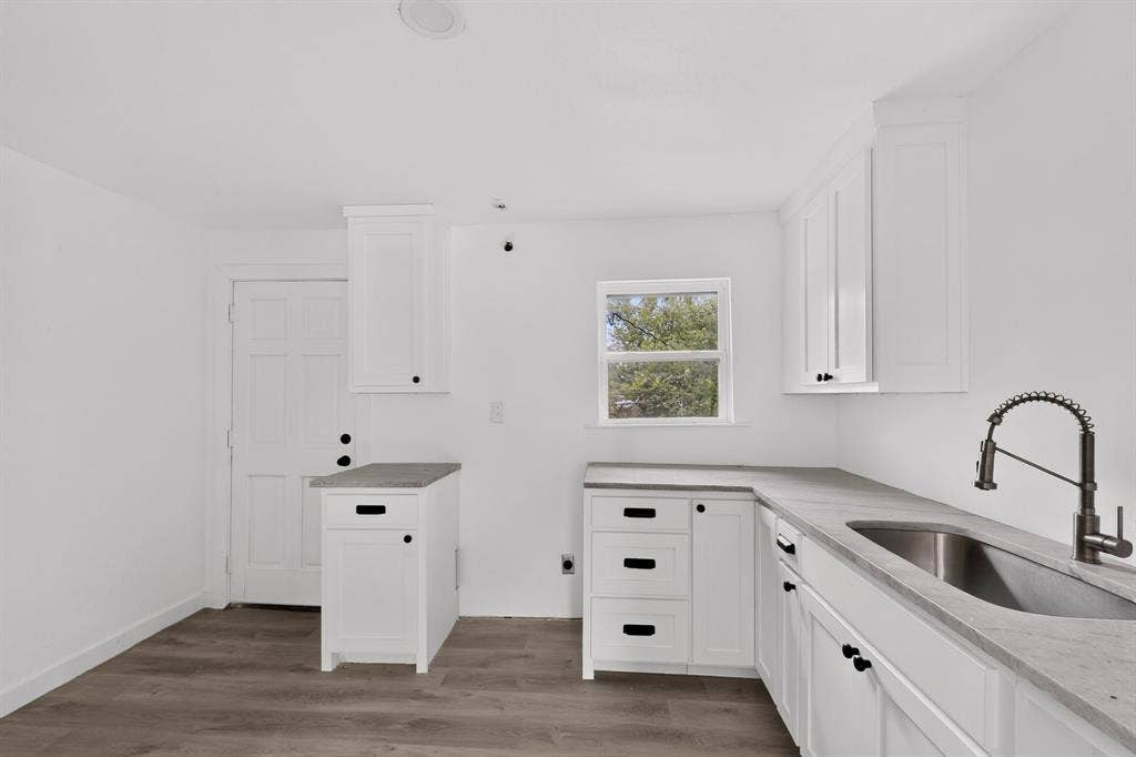 1831 Highland Street, Mesquite, TX 75149 Kitchen featuring white shaker-style cabinetry, solid-surface countertops, wood-finish flooring, undermount stainless steel sink, and high-arc pull-down faucet