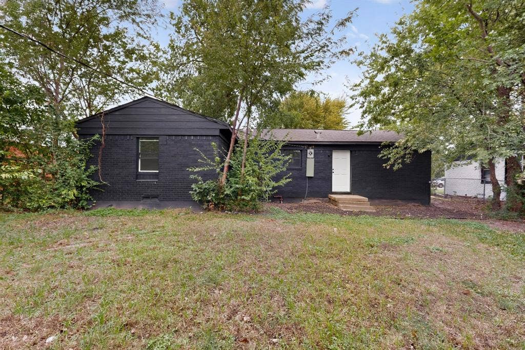 1831 Highland Street, Mesquite, TX 75149 Exterior featuring a black-painted masonry finish, horizontal siding gable, single-entry door, and mature surrounding trees