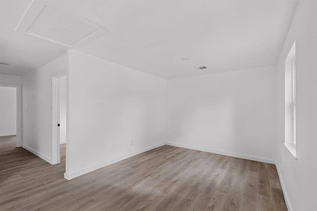1831 Highland Street, Mesquite, TX 75149 Neutral interior space featuring wood-finish flooring, crisp white walls, and a recessed ceiling access panel