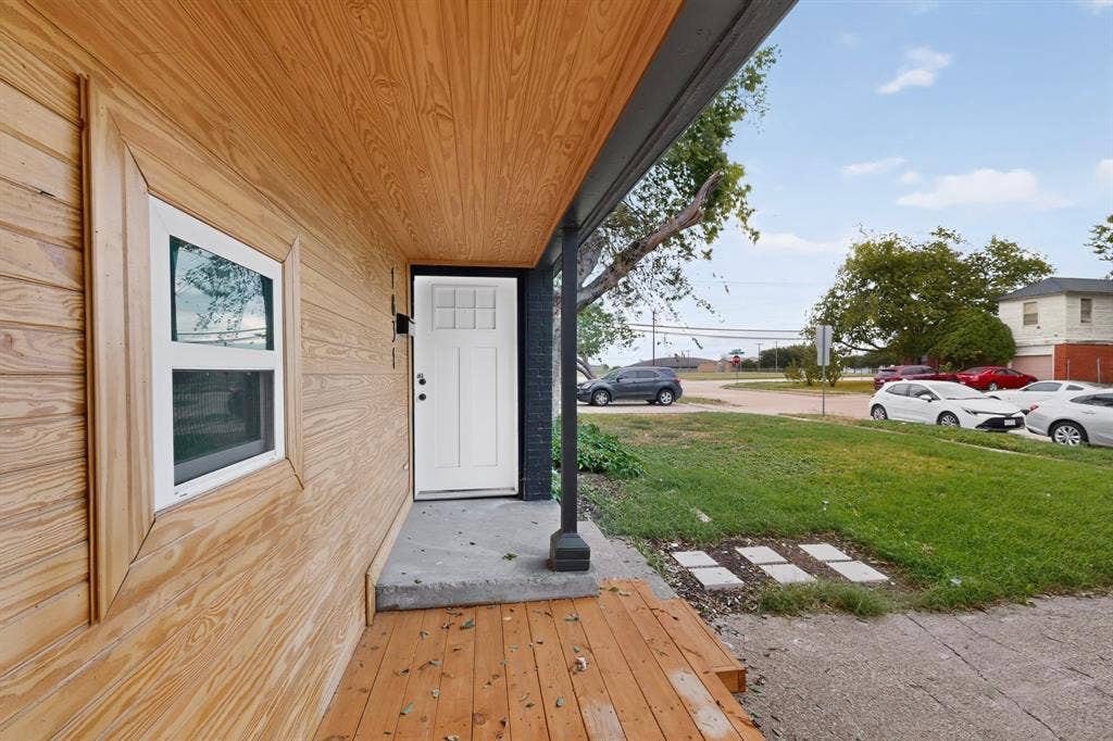 1831 Highland Street, Mesquite, TX 75149 Exterior entryway featuring wood-finish siding, a covered wood-plank porch, a multi-pane front door, and dark-finished structural column