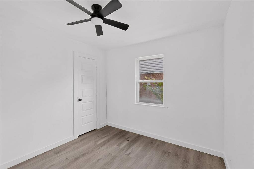 1831 Highland Street, Mesquite, TX 75149 Interior space featuring wood-finish flooring, a five-panel interior door, a single-hung window, and a matte black ceiling fan