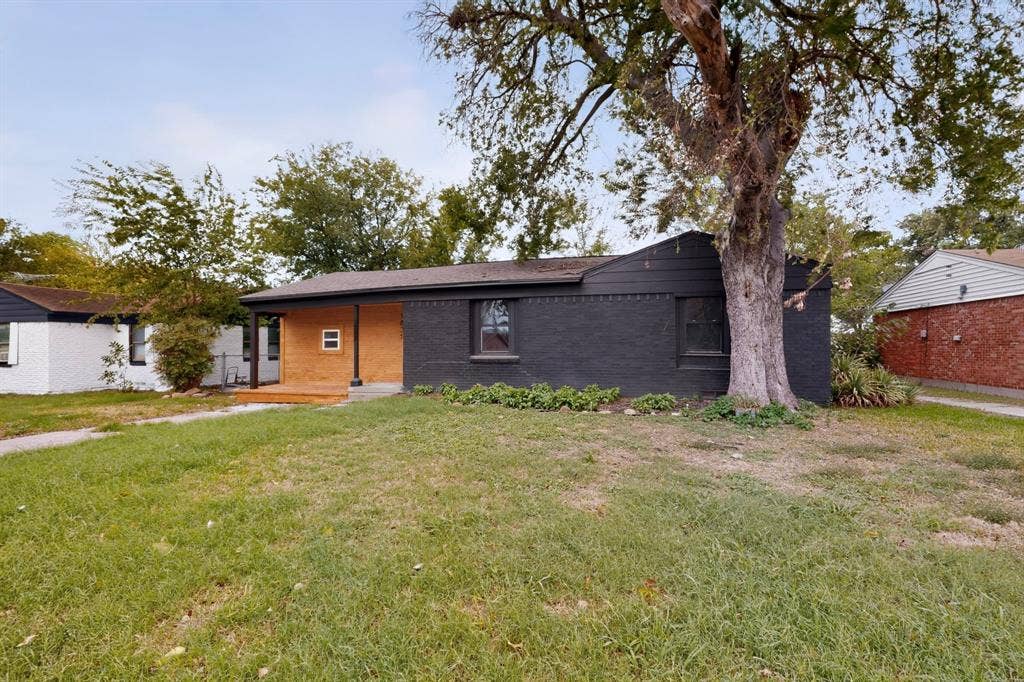 1831 Highland Street, Mesquite, TX 75149 Exterior facade featuring painted brick masonry, natural wood-finish porch siding, dark-toned trim, and a mature tree
