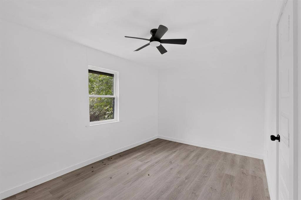 1831 Highland Street, Mesquite, TX 75149 Neutral-toned wood-finish flooring, white walls, and a modern ceiling fan with matte black finish