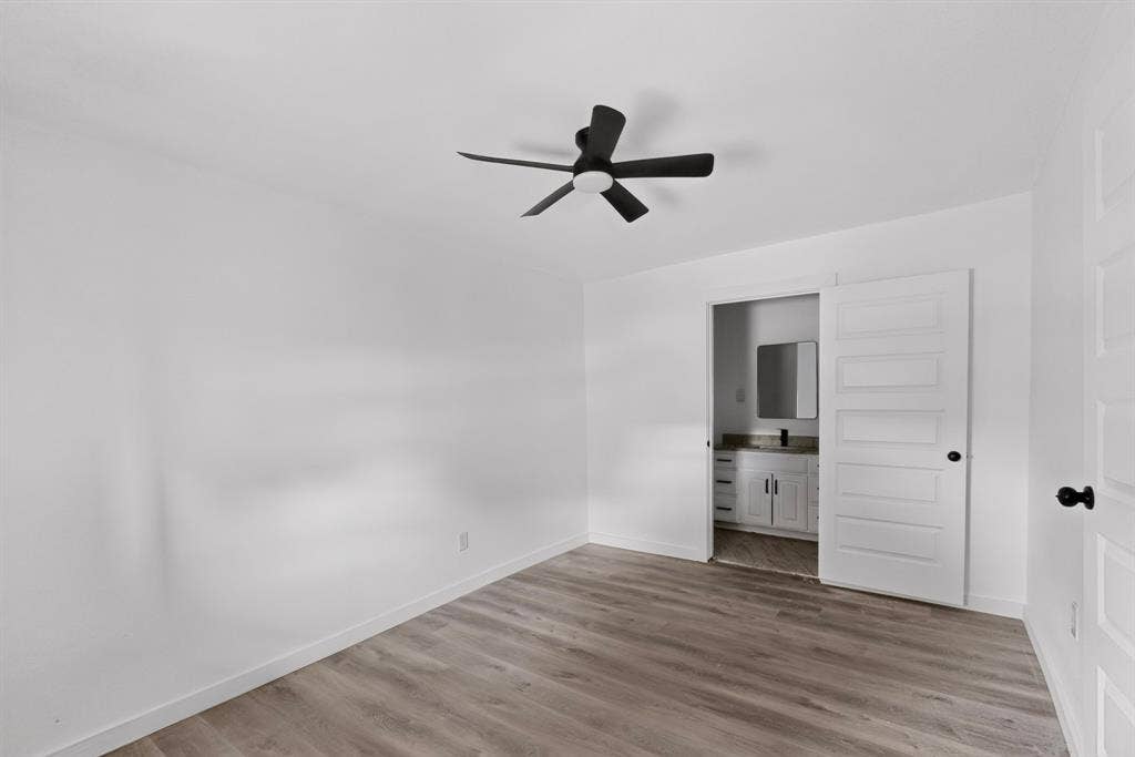 1831 Highland Street, Mesquite, TX 75149 Neutral interior featuring wood-finish flooring, a matte black ceiling fan with integrated lighting, and a five-panel interior door