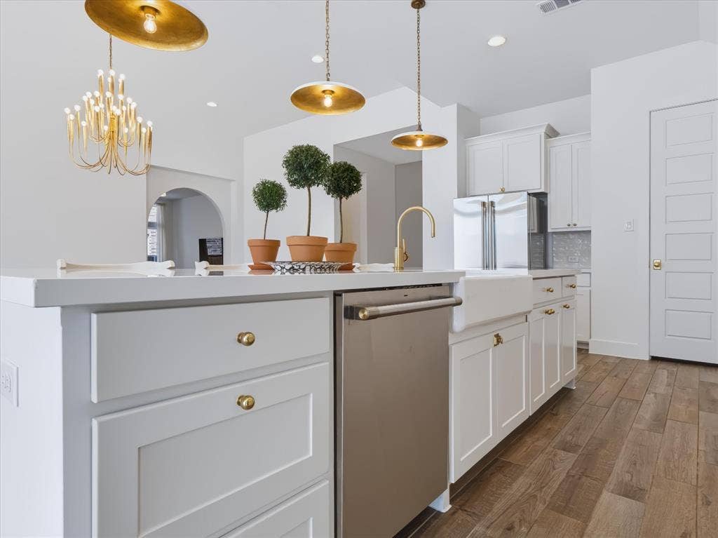1103 Sandgate Drive, Forney, TX 75126 Kitchen featuring a white island with cabinetry, farmhouse-style sink, brass-tone hardware, pendant lighting, and wood-finish flooring