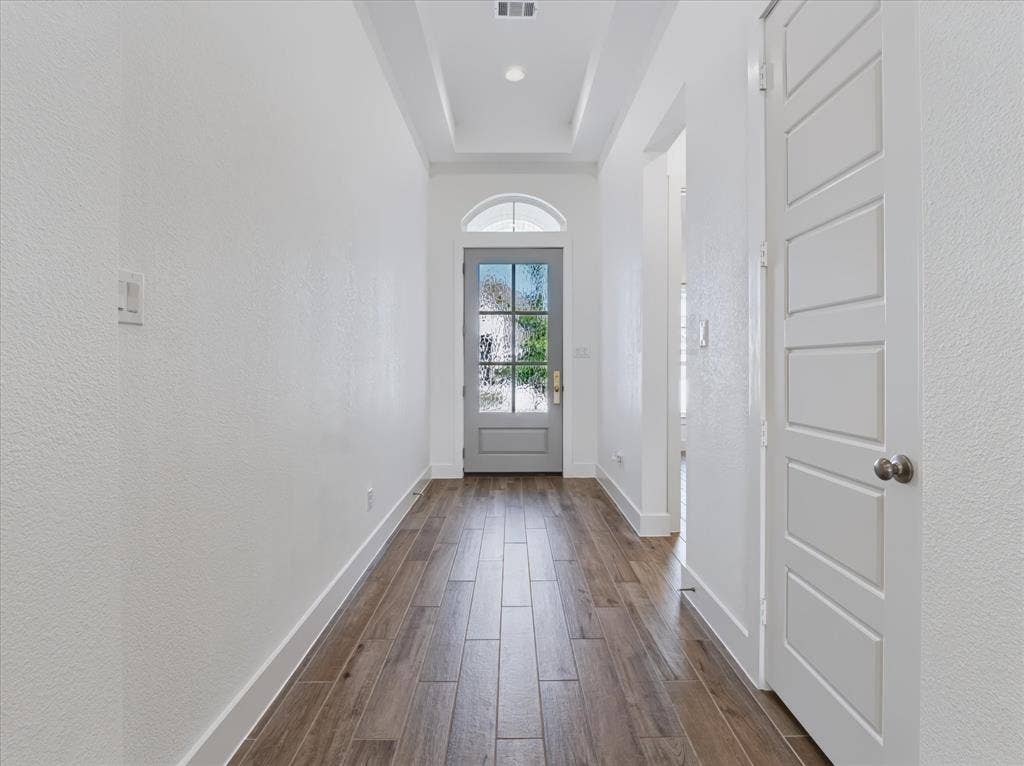 1103 Sandgate Drive, Forney, TX 75126 Entryway featuring wood-finish flooring, a tray ceiling, and a six-panel door with a glass-paned upper arch