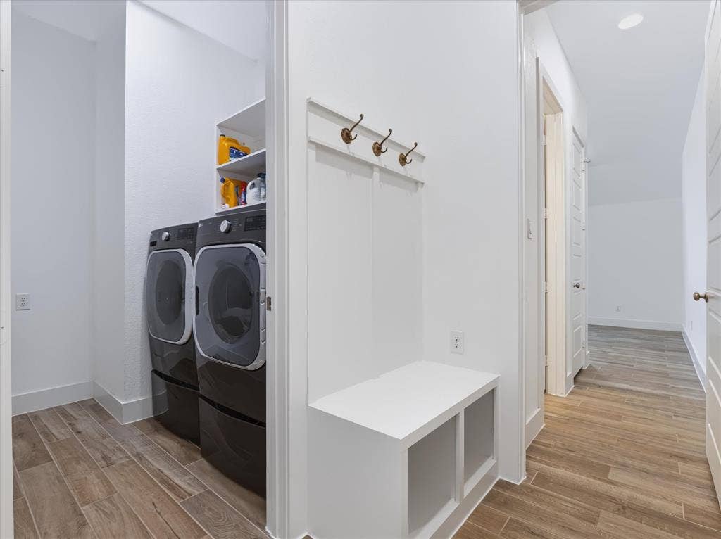 1103 Sandgate Drive, Forney, TX 75126 Built-in mudroom bench featuring integrated storage cubbies and a multi-hook coat rack, complemented by wood-finish tile flooring and an enclosed laundry area with recessed shelving
