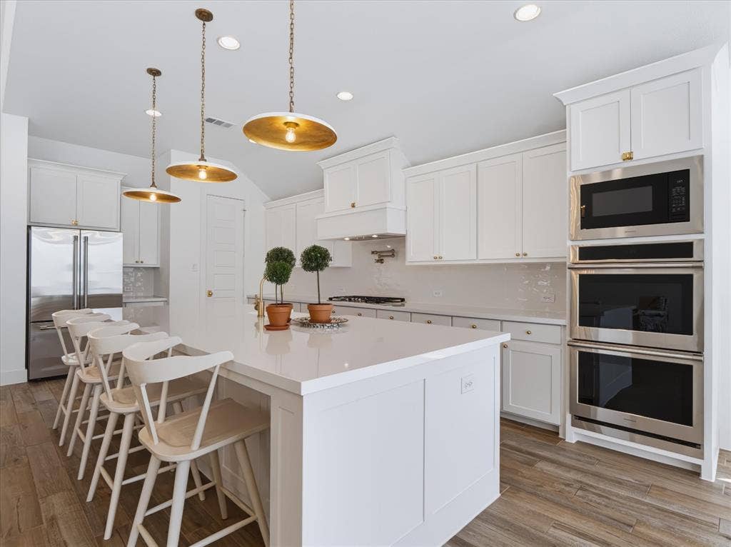 1103 Sandgate Drive, Forney, TX 75126 Kitchen featuring white cabinetry, quartz countertops, wood-finish flooring, stainless steel built-in double wall ovens, and pendant lighting