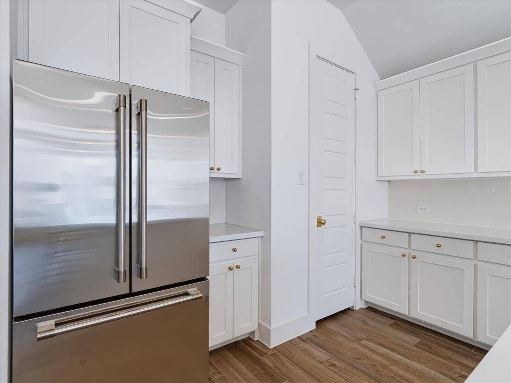 1103 Sandgate Drive, Forney, TX 75126 Kitchen area featuring white shaker-style cabinetry, stainless steel French door refrigerator, solid-surface countertops, and wood-finish flooring
