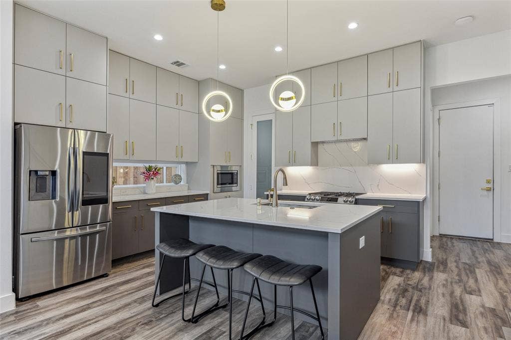 Kitchen with appliances with stainless steel finishes, a center island with sink, hardwood / wood-style flooring, and sink