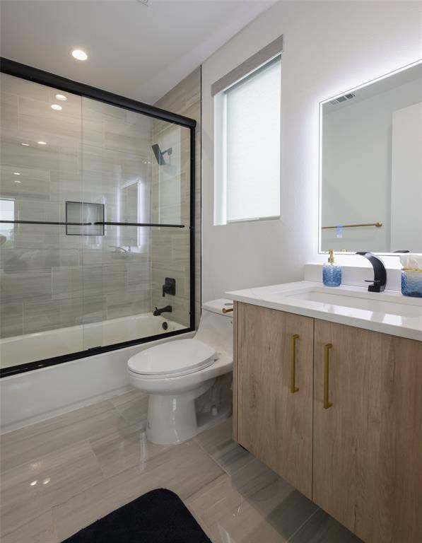 Full bathroom featuring enclosed tub / shower combo, tile patterned flooring, vanity, and toilet