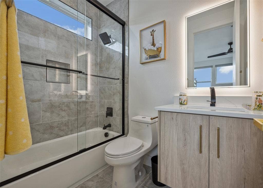Full bathroom featuring tile patterned flooring, vanity, a healthy amount of sunlight, and toilet
