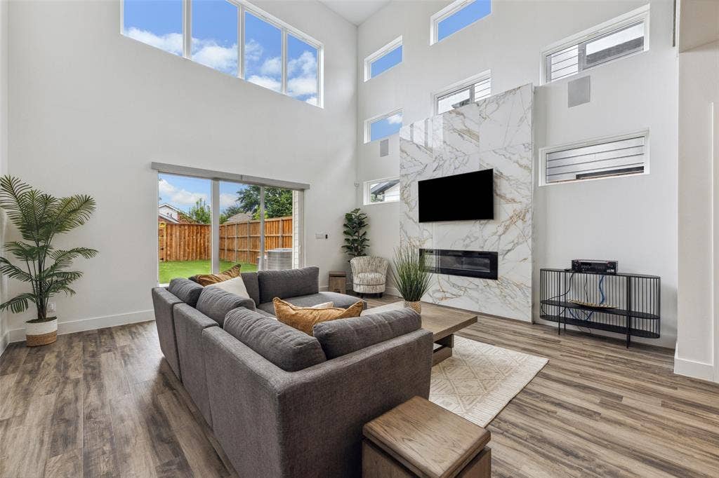 Living room with a towering ceiling, wood-type flooring, and a fireplace