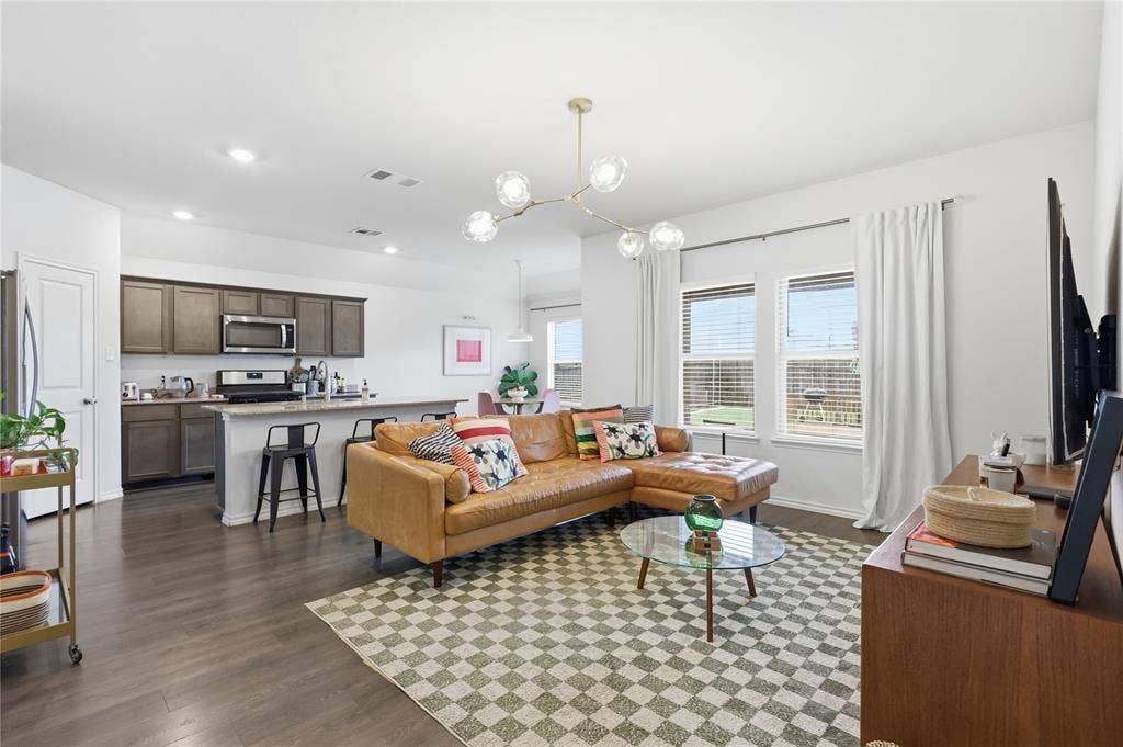 1108 Emerald Gate Drive, Princeton, TX 75407 Open-concept living space featuring wood-finish flooring, a kitchen with dark cabinetry and a central island, recessed lighting, and a multi-globe chandelier