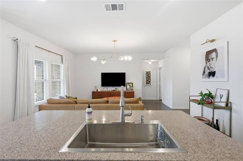 1108 Emerald Gate Drive, Princeton, TX 75407 Kitchen island featuring stone countertop, under-mount stainless steel sink, and high-arc pull-down faucet