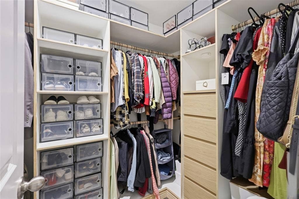 1108 Emerald Gate Drive, Princeton, TX 75407 Custom walk-in closet featuring white laminate shelving, stacked cubbies, tiered hanging rods, and a built-in chest of drawers with light-toned wood-finish fronts