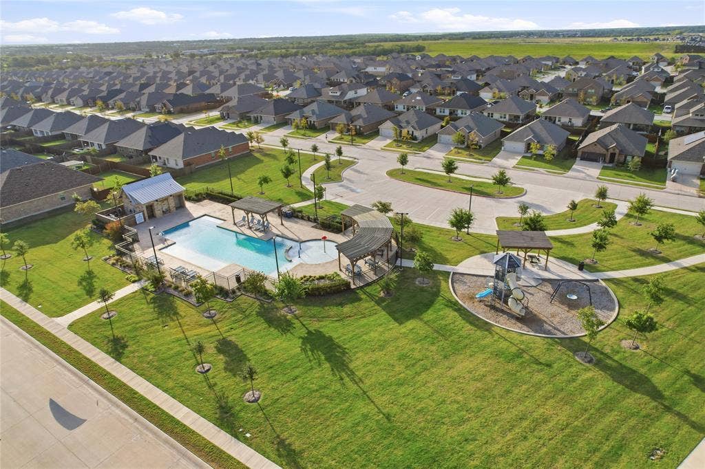 1108 Emerald Gate Drive, Princeton, TX 75407 Community amenities featuring an outdoor swimming pool, stone-clad poolside structure, multiple shaded pergolas, and a paved playground area set within landscaped grounds