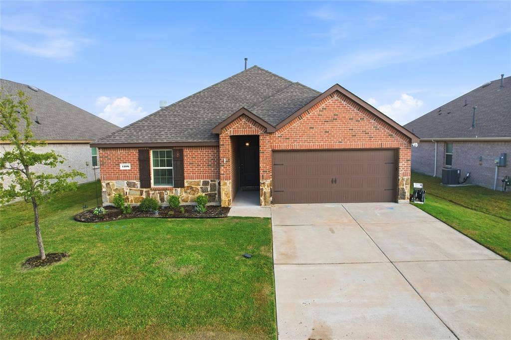 1108 Emerald Gate Drive, Princeton, TX 75407 Brick and stone facade exterior featuring a multi-gabled roofline, an attached two-car garage with a panel door, and concrete driveway