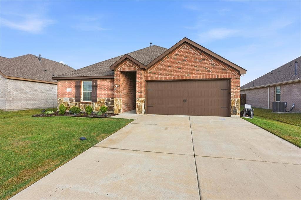 1108 Emerald Gate Drive, Princeton, TX 75407 Brick and stone exterior featuring a recessed entry, a multi-car garage, and shuttered windows