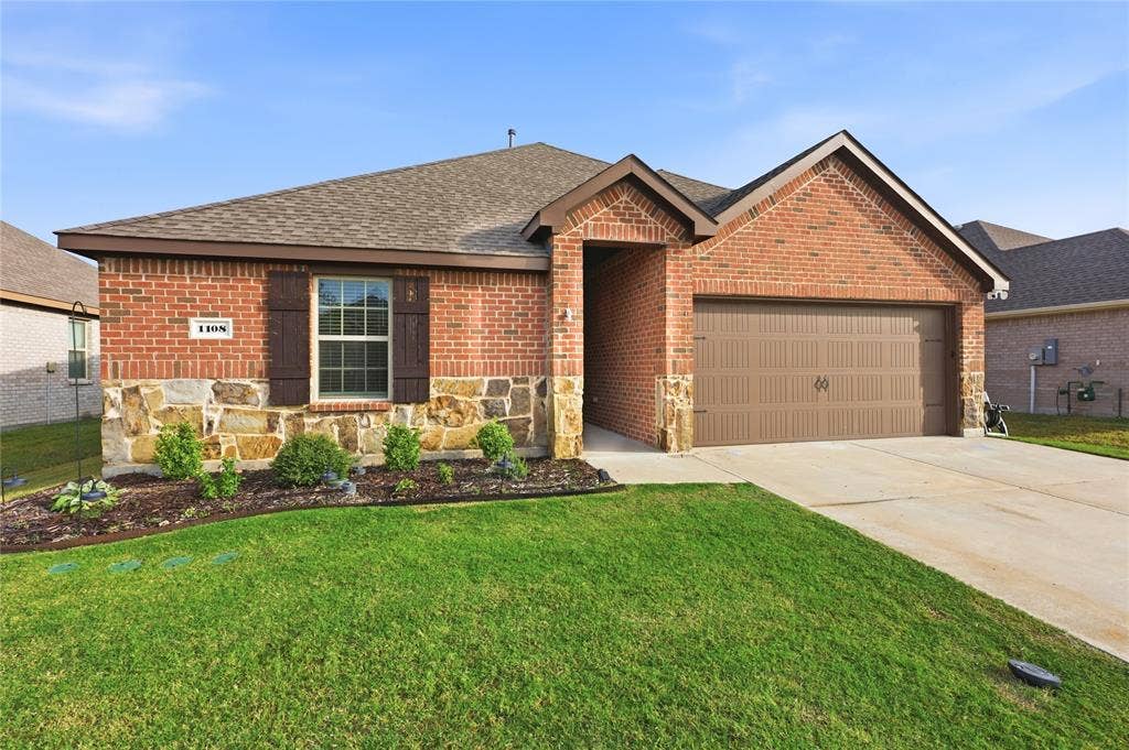 1108 Emerald Gate Drive, Princeton, TX 75407 Brick and stone veneer exterior with decorative shutters, a covered entryway, and an attached two-car garage