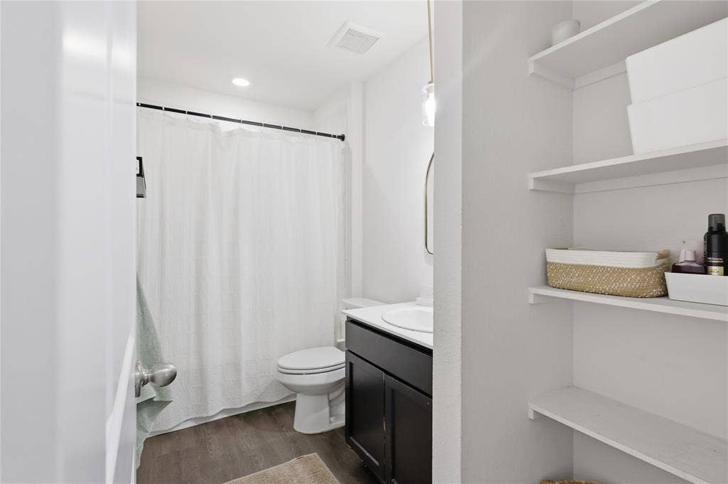 1108 Emerald Gate Drive, Princeton, TX 75407 Bathroom featuring wood-finish flooring, a dark-toned vanity with a white countertop, recessed lighting, and built-in wall shelving