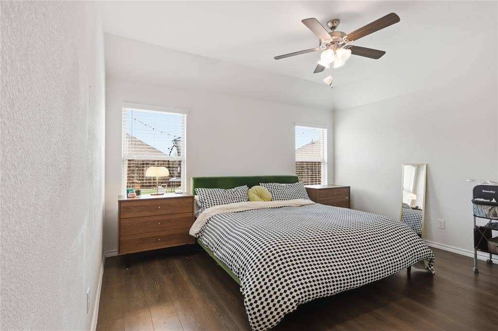1108 Emerald Gate Drive, Princeton, TX 75407 Room featuring wood-finish flooring, high tray ceilings, two windows, and a multi-blade ceiling fan with integrated light fixture