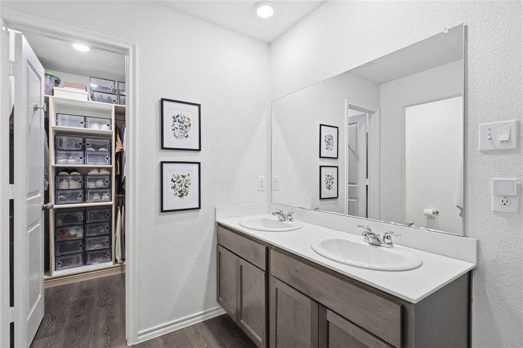 1108 Emerald Gate Drive, Princeton, TX 75407 Double vanity with stone-surface countertop, dual drop-in sinks, chrome finish fixtures, and full-width wall mirror