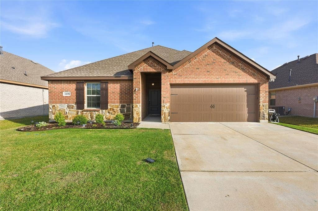 1108 Emerald Gate Drive, Princeton, TX 75407 Single-story residence with a brick and stone facade, gabled roofline, shuttered windows, and a two-car attached garage