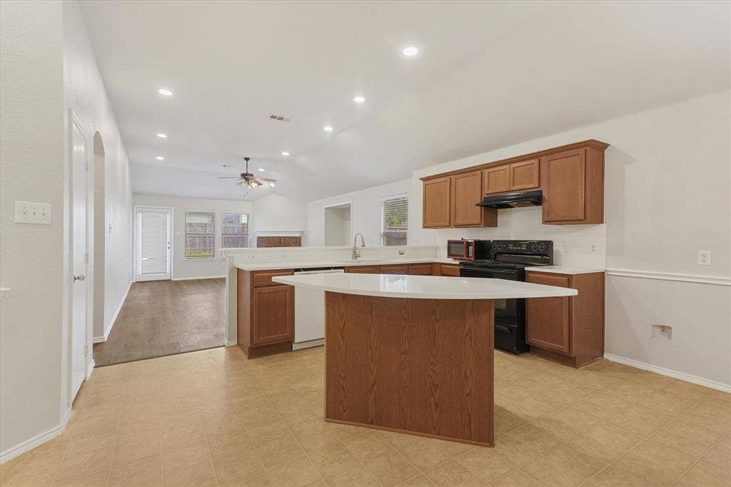 2004 Athabasca Falls Drive, Anna, TX 75409 Kitchen featuring wood cabinetry, a central island with a solid-surface countertop, recessed lighting, and tile flooring