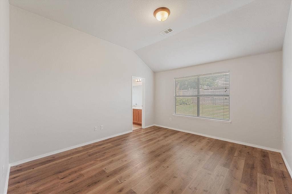 2004 Athabasca Falls Drive, Anna, TX 75409 Vaulted ceiling with neutral wall tones, wood-finish flooring, and a single-pane window with integrated horizontal blinds